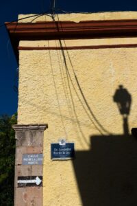 Freileitungen und eine Straßenlaterne werfen Schatten auf eine Hauswand