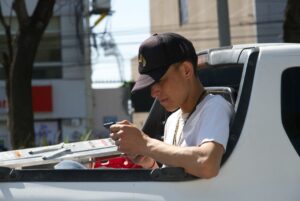 Ein junger Mann sitzt auf der Ladefläche eines Pickups und schaut in sein Handy