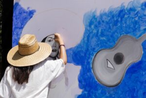 Eine Frau malt eine Frau und eine Gitarre