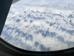 Blick aus dem Flugzeug auf Packeis und Wolken