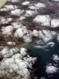 Blick aus dem Flugzeug auf eine Küstenstadt an den großen Seen mit kleinen Schönwetterwölkchen.